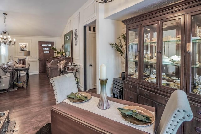 dining room with an inviting chandelier, dark hardwood / wood-style floors, vaulted ceiling, and crown molding