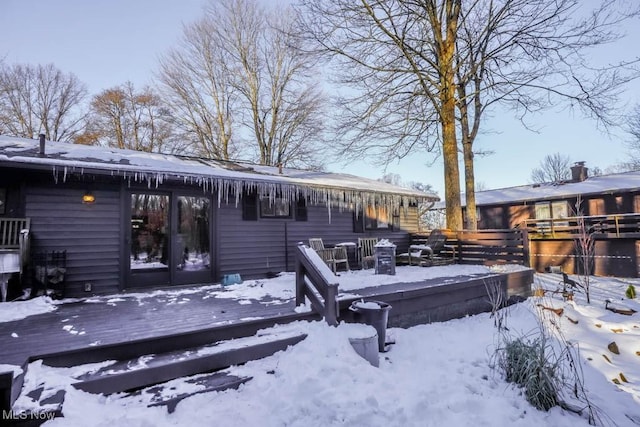 snow covered back of property with a wooden deck