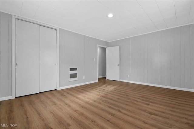 unfurnished bedroom with hardwood / wood-style floors, a closet, and heating unit