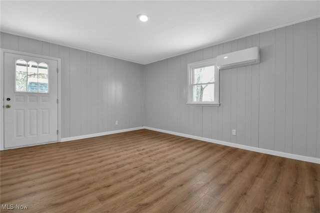 foyer entrance featuring a wall mounted air conditioner, hardwood / wood-style flooring, plenty of natural light, and wood walls