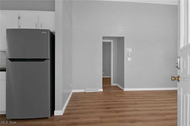 kitchen with white cabinetry, stainless steel refrigerator, and light hardwood / wood-style flooring