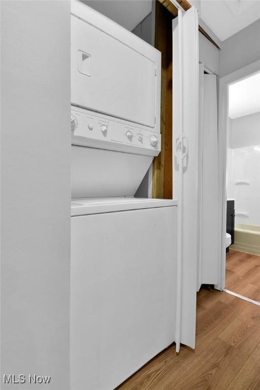 laundry room featuring stacked washer and dryer and light hardwood / wood-style floors