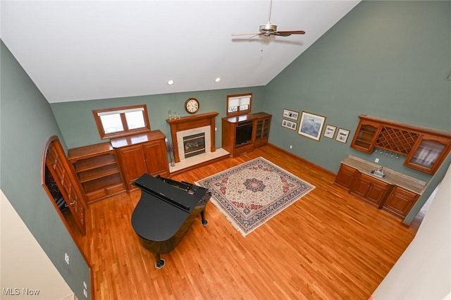 living room with ceiling fan, a fireplace, wood-type flooring, and lofted ceiling