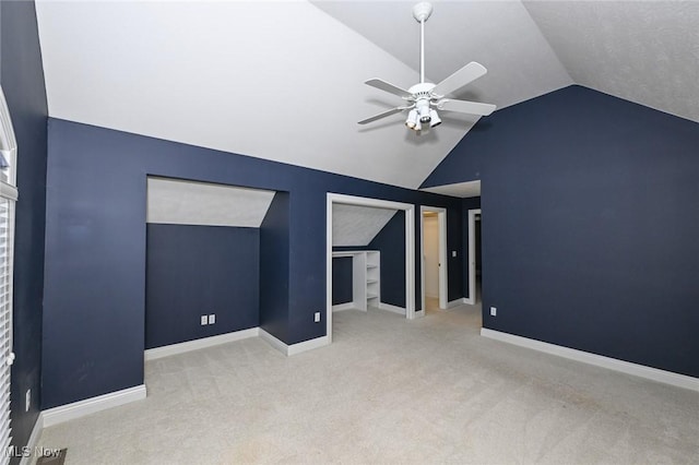 interior space with ceiling fan, light carpet, and vaulted ceiling