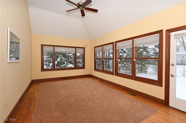 unfurnished room with a wealth of natural light, light hardwood / wood-style flooring, and vaulted ceiling