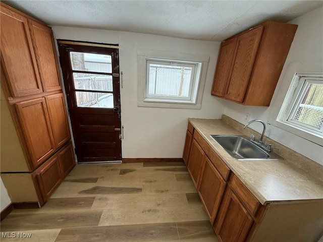 kitchen with a sink, light wood-style flooring, and brown cabinetry