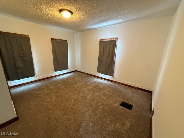 unfurnished room featuring carpet flooring, visible vents, a textured ceiling, and baseboards