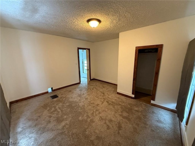 empty room featuring baseboards, carpet floors, a textured ceiling, and visible vents