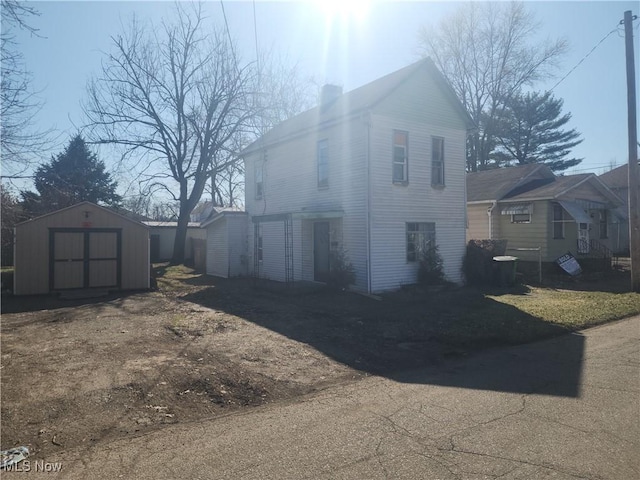 view of home's exterior with an outbuilding, a shed, and a chimney