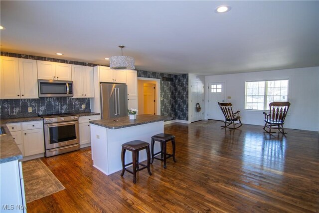 kitchen with white cabinets, pendant lighting, premium appliances, and a kitchen island