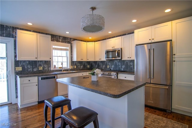 kitchen featuring a breakfast bar area, white cabinetry, decorative light fixtures, and premium appliances