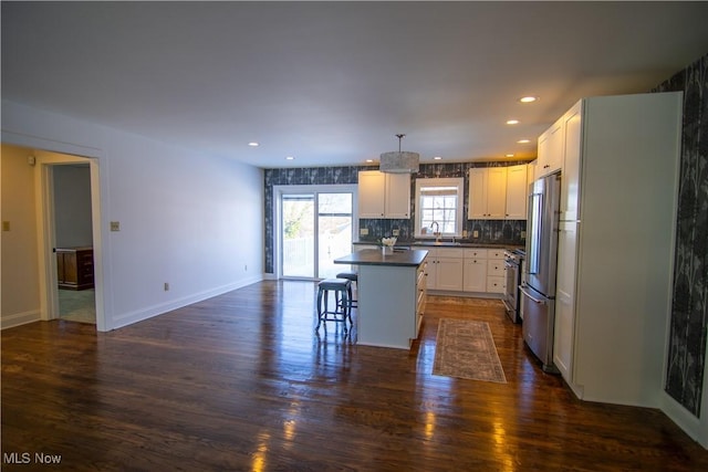 kitchen with a center island, backsplash, a kitchen breakfast bar, sink, and white cabinetry