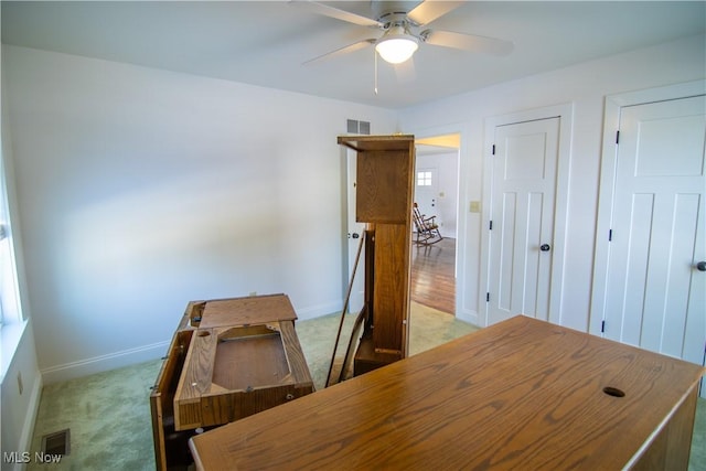 unfurnished office featuring light carpet and ceiling fan