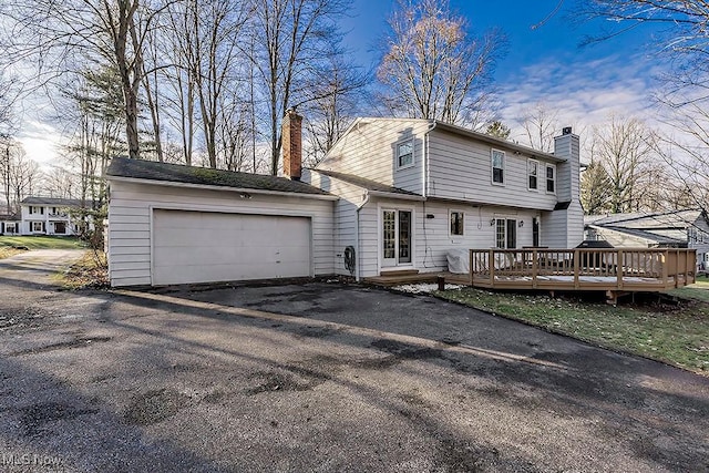 rear view of property with a wooden deck and a garage