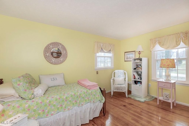 bedroom with hardwood / wood-style floors and multiple windows