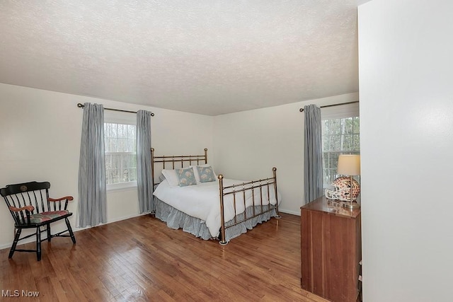 bedroom featuring a textured ceiling, hardwood / wood-style flooring, and multiple windows