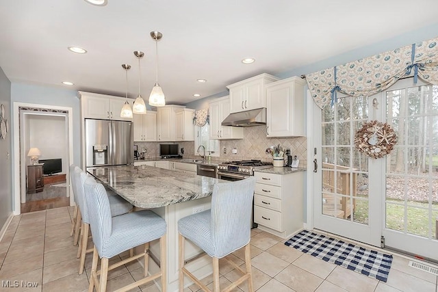 kitchen featuring white cabinets, appliances with stainless steel finishes, decorative light fixtures, and decorative backsplash