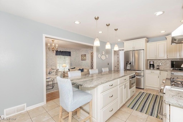 kitchen featuring light stone countertops, stainless steel appliances, a kitchen breakfast bar, decorative light fixtures, and a kitchen island