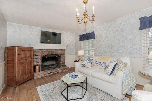 living room featuring a fireplace, wood-type flooring, and a notable chandelier