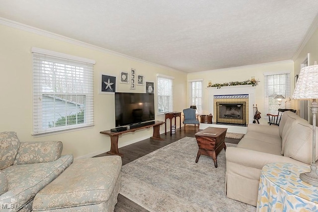 living room with hardwood / wood-style floors, a textured ceiling, crown molding, and a tiled fireplace