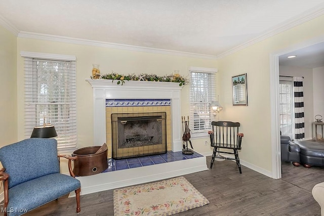 sitting room with a tiled fireplace, crown molding, and dark hardwood / wood-style flooring