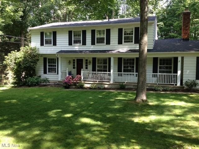 colonial inspired home featuring a porch and a front yard