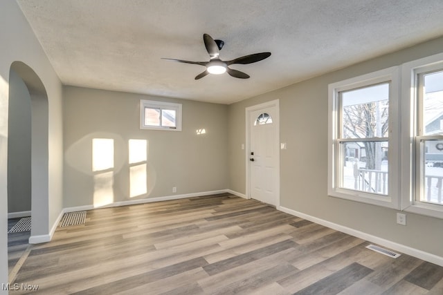 foyer entrance with ceiling fan, light hardwood / wood-style floors, and a textured ceiling