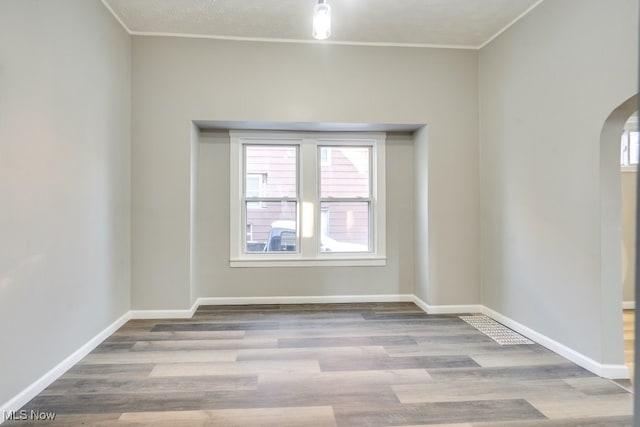 empty room with light wood-type flooring and crown molding