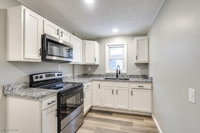 kitchen featuring a textured ceiling, stainless steel appliances, white cabinetry, and sink