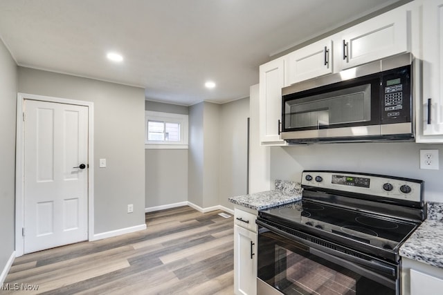 kitchen featuring light stone countertops, white cabinetry, appliances with stainless steel finishes, and light hardwood / wood-style flooring