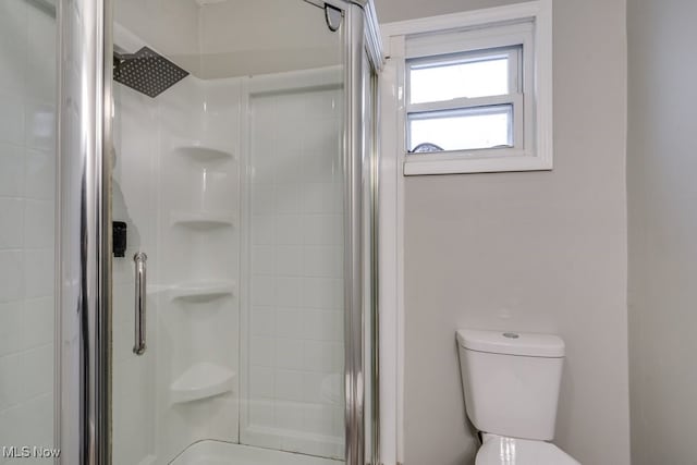 bathroom featuring a shower with shower door and toilet