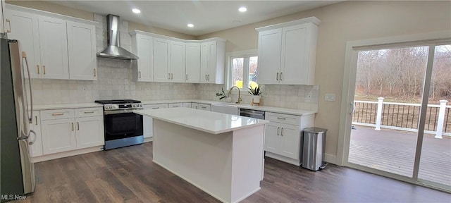 kitchen with dark hardwood / wood-style flooring, wall chimney exhaust hood, stainless steel appliances, a center island, and white cabinetry