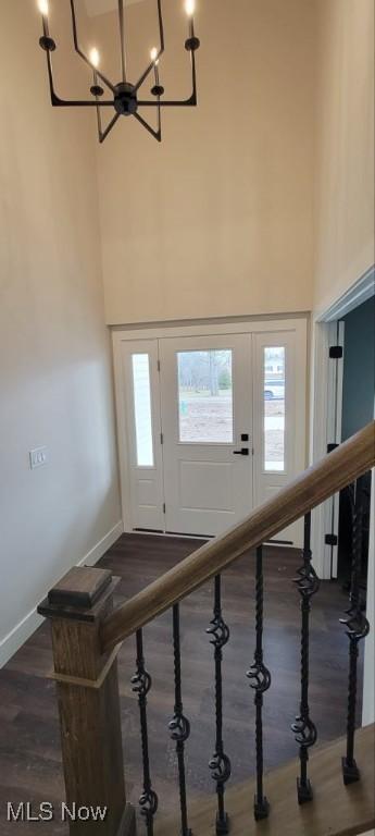 foyer entrance featuring a towering ceiling, dark hardwood / wood-style flooring, and a notable chandelier