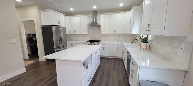 kitchen with wall chimney exhaust hood, a center island, white cabinets, and appliances with stainless steel finishes