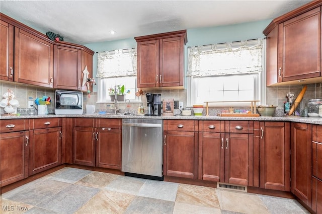 kitchen with stainless steel dishwasher, sink, light stone counters, and backsplash