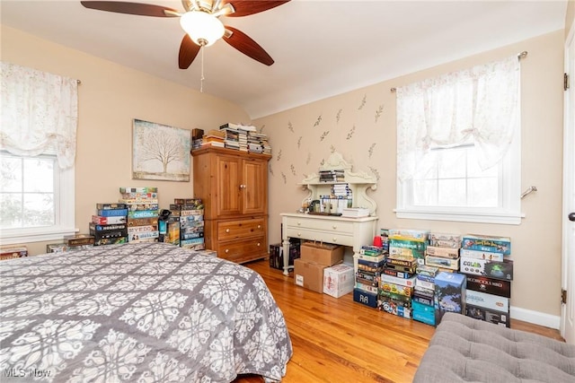 bedroom with ceiling fan, vaulted ceiling, and light wood-type flooring