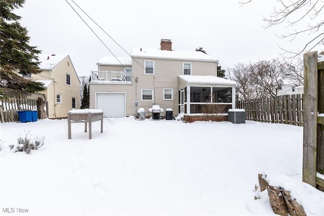 snow covered house featuring a sunroom, a balcony, and central AC