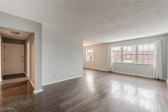 unfurnished room with dark wood-type flooring and a textured ceiling