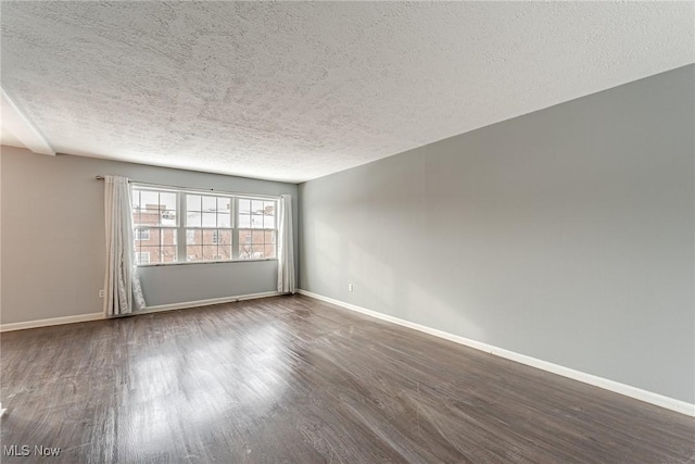 spare room with dark hardwood / wood-style flooring and a textured ceiling