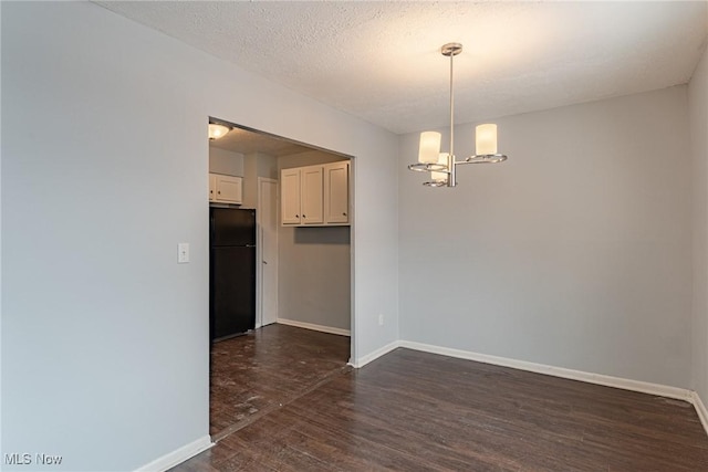 unfurnished dining area featuring a notable chandelier, dark hardwood / wood-style floors, and a textured ceiling