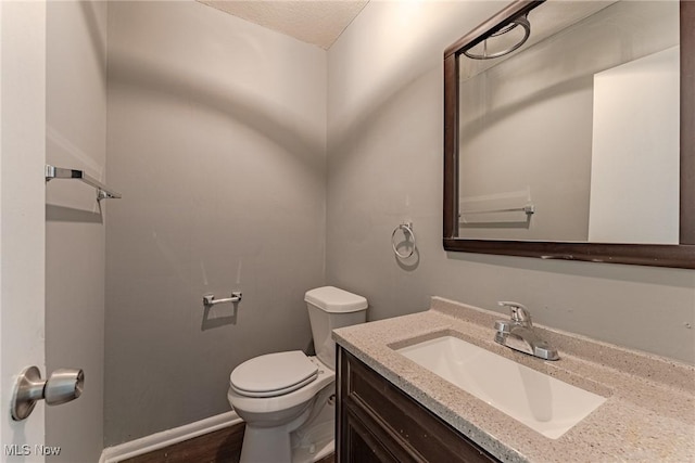 bathroom featuring a textured ceiling, vanity, and toilet