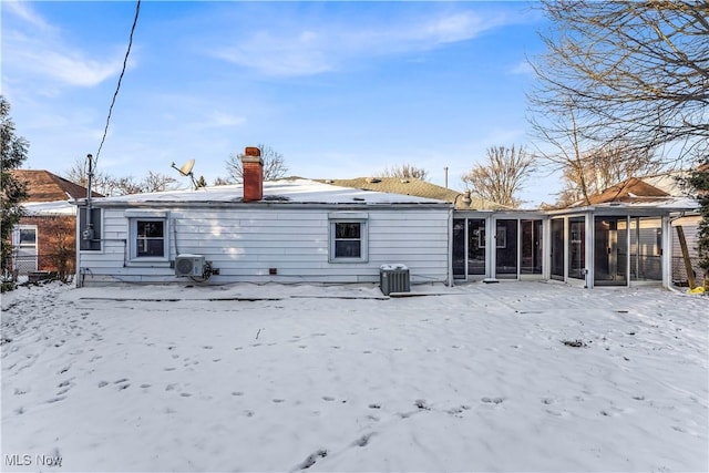 snow covered back of property with a sunroom and cooling unit