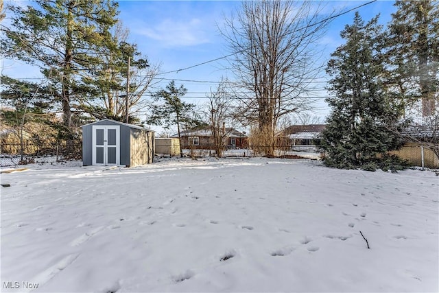 snowy yard featuring a storage shed