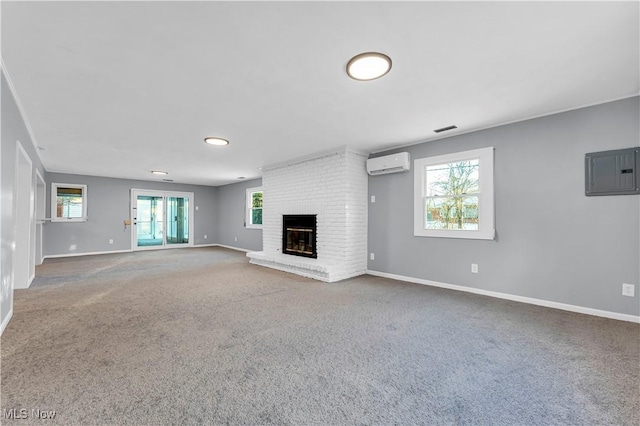 unfurnished living room with a brick fireplace, electric panel, an AC wall unit, and a wealth of natural light