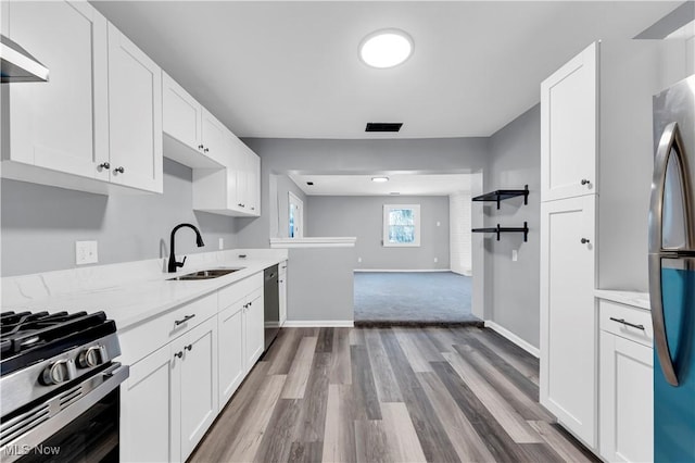 kitchen featuring white cabinetry, sink, stainless steel appliances, light stone counters, and light hardwood / wood-style flooring