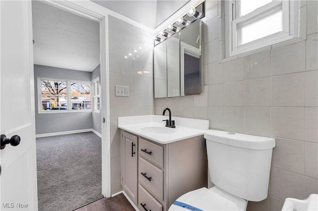 bathroom with vanity, toilet, and tile walls