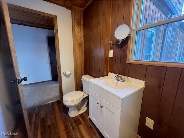 bathroom with hardwood / wood-style floors, vanity, toilet, and wooden walls