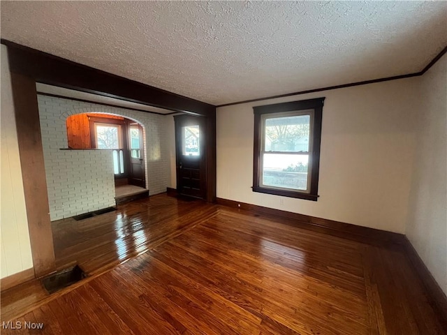 spare room featuring a textured ceiling, crown molding, and dark wood-type flooring