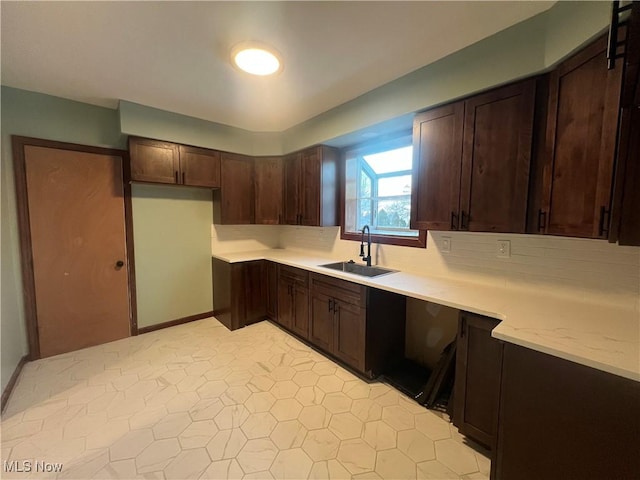 kitchen featuring backsplash, dark brown cabinetry, and sink