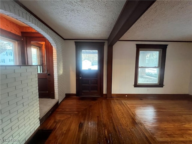 entryway featuring dark wood-type flooring, a textured ceiling, and ornamental molding